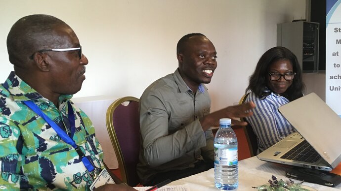 Three sitting, smiling Ghanaian team members