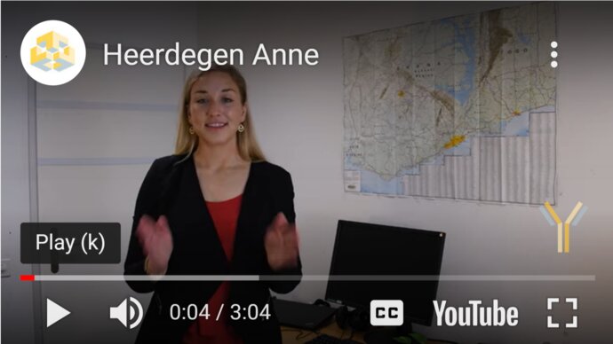 YouTube still of a blond European woman in a suite standing and talking
