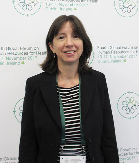 Smiling lady in a black jacket in front of an exhibition panel