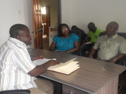 CRT members interviewing a district-level stakeholder A woman and three men meet around a desk in an office