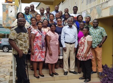 A group of African men and women standing on steps and looking at the camera