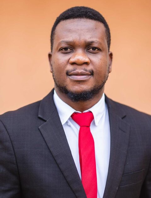 Head a shoulders shot of an African man in a dark suit and red tie