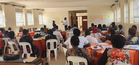 Facilitator from Makerere School of Public Health leading a discussion about leadership skills Man standing at the front of a room, talking to lots of seated people