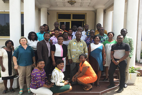 A group of African men and women posing on the steps of a building with columns