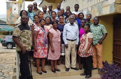 A group of African men and women standing smiling on steps outside a building